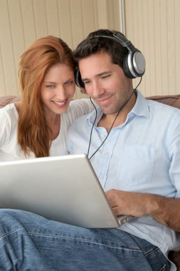 Happy couple listening to music on laptop computer clipart