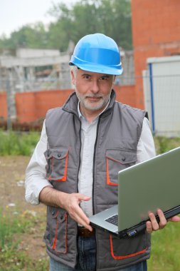 Site manager with laptop computer checking construction clipart