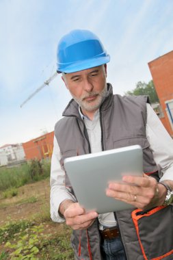 Site manager using electronic tablet clipart