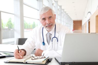 Portrait of senior doctor in office clipart