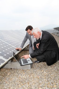 Businessmen checking solar panels running clipart