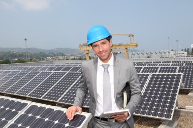 Businessman standing on solar panel installation clipart