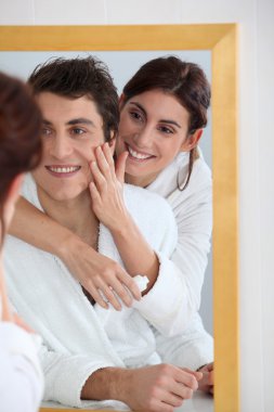 Woman applying moisturizer on boyfriend's cheek clipart