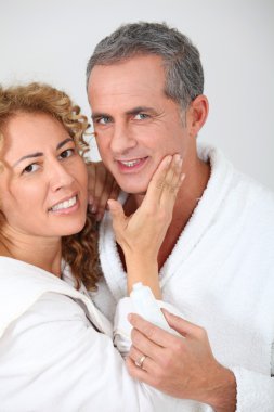 Woman applying moisturizer on boyfriend's cheek clipart