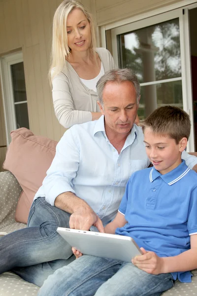 Familie sitzt auf Couch mit elektronischem Tablet — Stockfoto