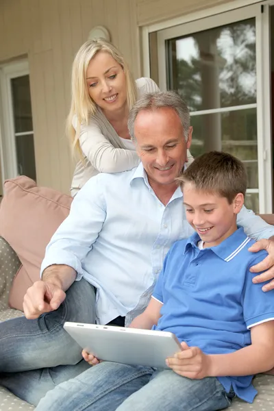 Семья сидит на диване с электронным планшетом — стоковое фото