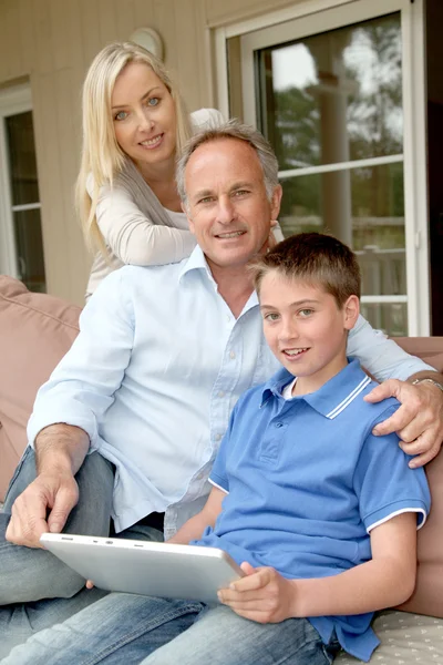 Οικογένεια κάθεται σε καναπέ με ηλεκτρονικό, ταμπλετών — Φωτογραφία Αρχείου