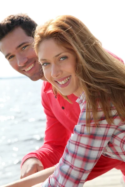 Retrato de pareja sonriente de pie junto a un lago — Foto de Stock