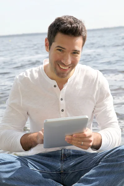 Knappe man zit op een ponton met touchpad — Stockfoto