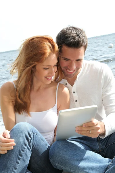 Casal usando tablet eletrônico em um lago — Fotografia de Stock