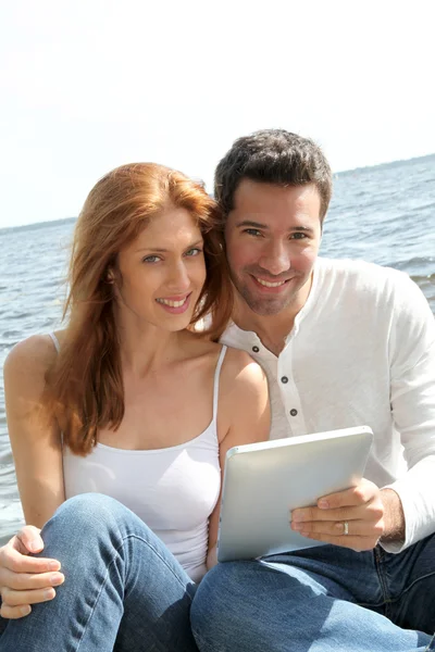 Couple utilisant une tablette électronique près d'un lac — Photo
