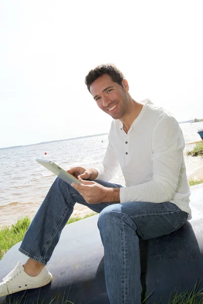 人坐在湖畔与电子平板电脑 — 图库照片