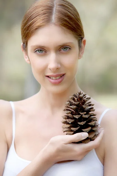 Retrato de mujer hermosa sosteniendo cono de pino — Foto de Stock