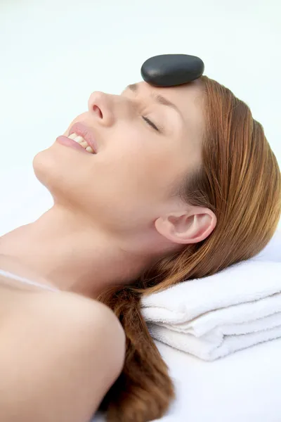 Žena položila na masážní lůžko s horkými kameny na čele — Stock fotografie