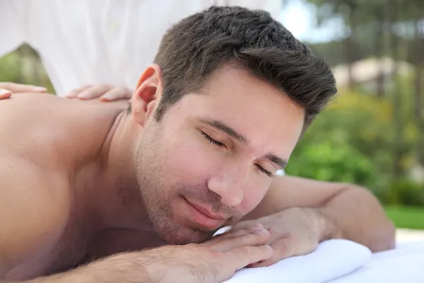 Hombre acostado en una cama de masaje — Foto de Stock