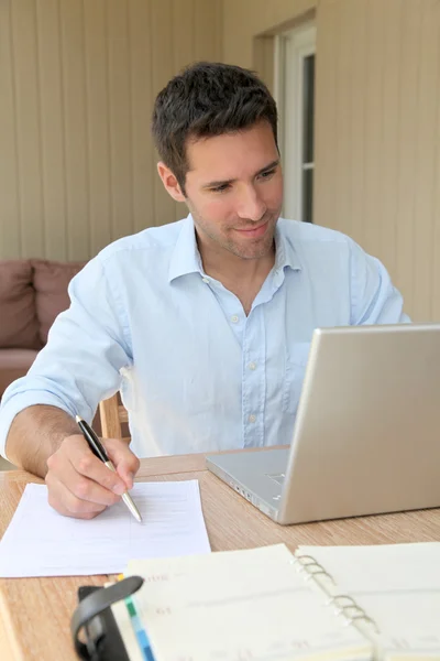 Усміхнений чоловік працює вдома на ноутбуці — стокове фото