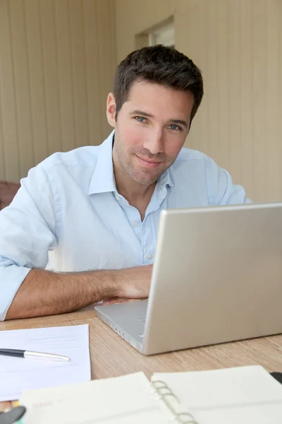 Usmívající se muž pracuje doma na přenosném počítači — Stock fotografie