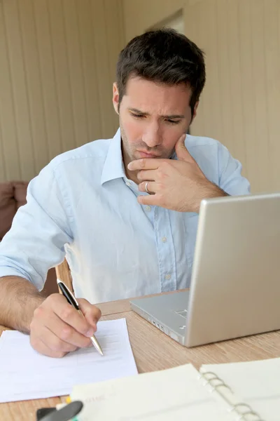 Усміхнений чоловік працює вдома на ноутбуці — стокове фото