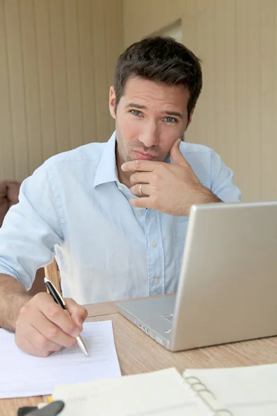 Uśmiechnięty mężczyzna pracujący w domu na komputerze przenośnym — Zdjęcie stockowe