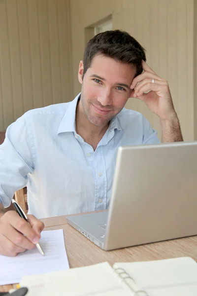 Usmívající se muž pracuje doma na přenosném počítači — Stock fotografie