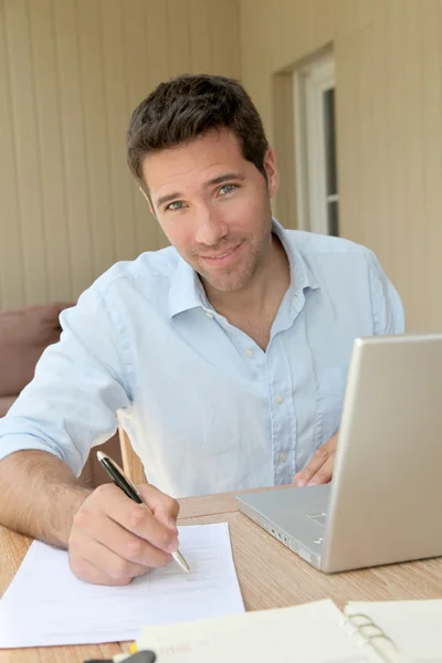 Homme souriant travaillant à la maison sur ordinateur portable — Photo