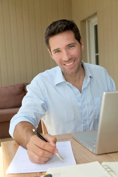 微笑在便携式计算机上在家里工作的人 — 图库照片