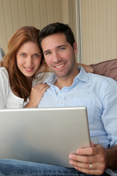 Paret sitter i soffan med bärbar dator — Stockfoto