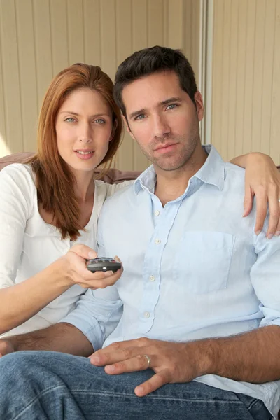 Paar sitzt auf Sofa mit Fernbedienung — Stockfoto