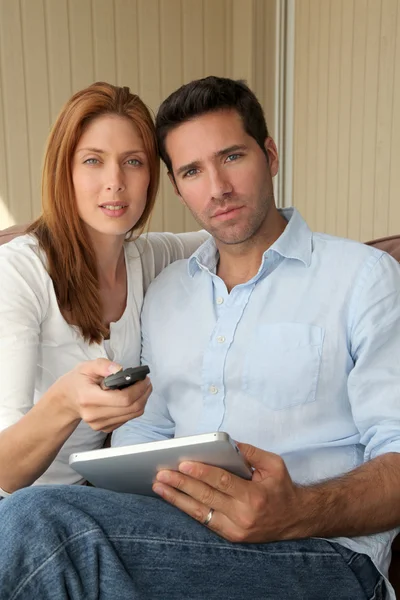 Paar zitten in Bank met tv remote control — Stockfoto