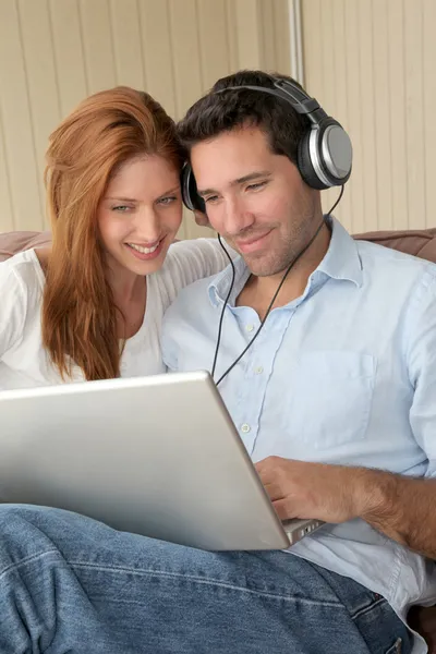 Szczęśliwa para słuchania muzyki na komputerze przenośnym — Zdjęcie stockowe