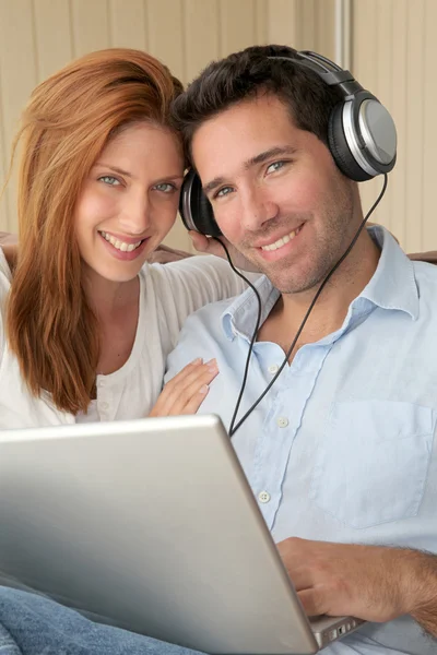 Szczęśliwa para słuchania muzyki na komputerze przenośnym — Zdjęcie stockowe