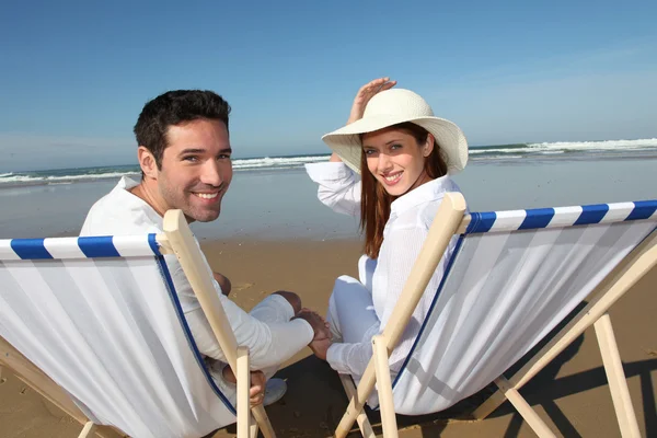 坐在 longchairs 在海滩上的情侣 — 图库照片