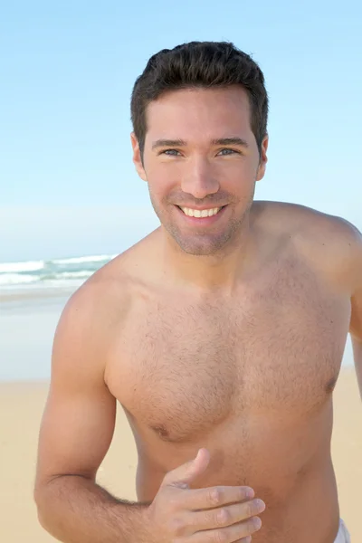 Χαμογελαστός άνθρωπος τζόκινγκ σε μια αμμώδη παραλία — Φωτογραφία Αρχείου