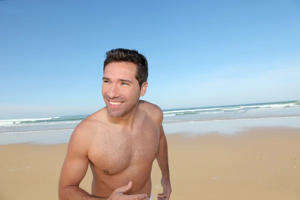 Uśmiechnięty mężczyzna jogging na plaży — Zdjęcie stockowe