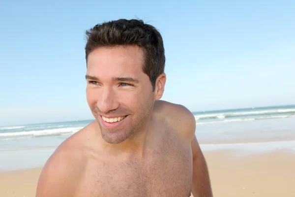 Усміхнений чоловік біжить на піщаному пляжі — стокове фото