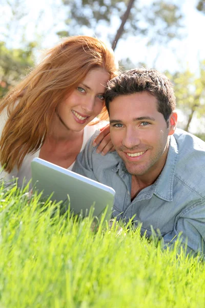 Retrato de pareja tumbando la hierba con touchpad — Foto de Stock