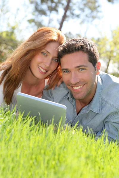 Portrat páru, se stanoví v trávě s touchpadem — Stock fotografie