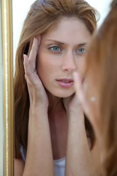 Mooie vrouw op zoek in een spiegel — Stockfoto