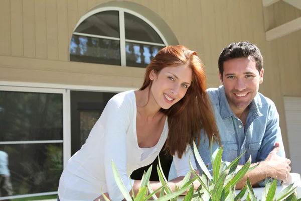 Jovem casal sentado na frente de sua nova casa — Fotografia de Stock