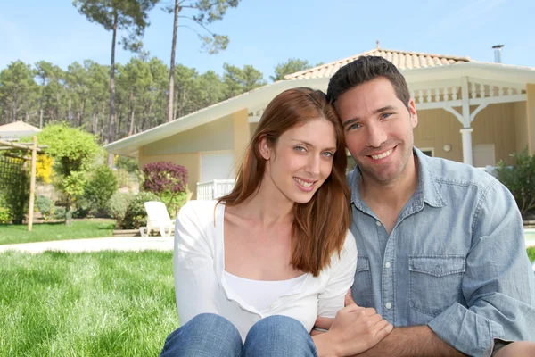 Pareja joven sentada frente a su nueva casa — Foto de Stock