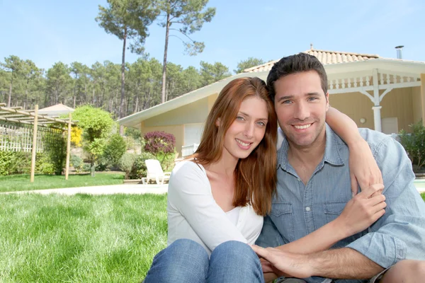 Jovem casal sentado na frente de sua nova casa — Fotografia de Stock