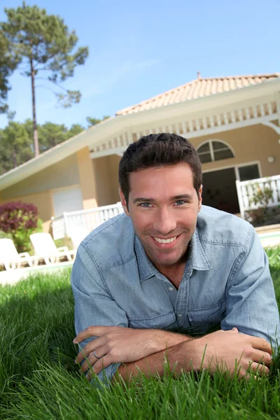 Sonriente hombre acostado casa jardín — Foto de Stock