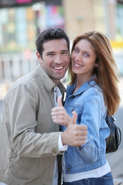 Happy couple with thumbs up in town — Stockfoto