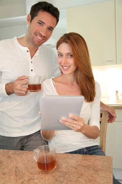 Młoda para przy użyciu elektronicznego komputera typu tablet w domu kuchnia — Zdjęcie stockowe
