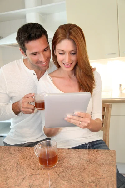 Jeune couple utilisant une tablette électronique dans la cuisine de la maison — Photo
