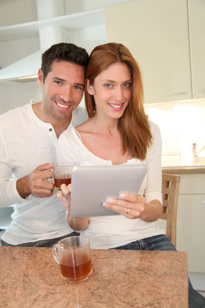 Casal jovem usando tablet eletrônico na cozinha doméstica — Fotografia de Stock