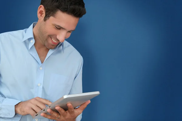 Aantrekkelijke man met touchpad op blauwe achtergrond — Stockfoto