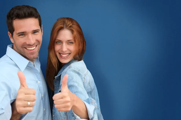 Pareja mostrando pulgares hacia arriba sobre fondo azul — Foto de Stock