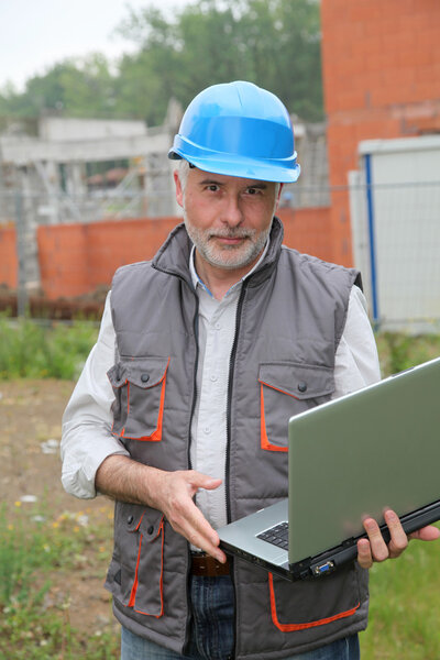 Site manager with laptop computer checking construction