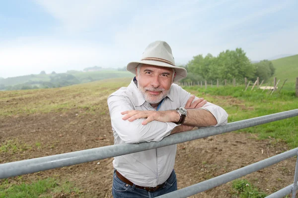 Agricoltore appoggiato sulla recinzione dei terreni agricoli — Foto Stock